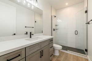 Bathroom with hardwood / wood-style flooring, vanity, an enclosed shower, and toilet