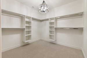 Spacious closet with light colored carpet and a chandelier