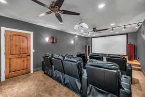 Home theater room featuring carpet, track lighting, and ceiling fan