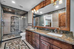 Bathroom featuring tile walls, tile patterned flooring, vanity, a shower with shower door, and toilet