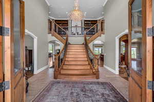 Entryway with a towering ceiling, ornamental molding, and a notable chandelier