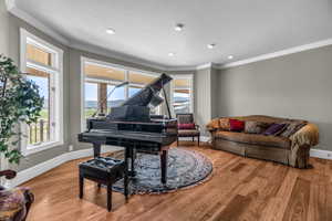 Sitting room with crown molding and light wood-type flooring