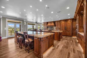 Kitchen with premium range hood, a breakfast bar area, ornamental molding, plenty of natural light, and a large island