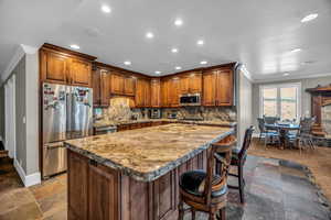 Kitchen with crown molding, stainless steel appliances, a kitchen breakfast bar, a center island, and tasteful backsplash