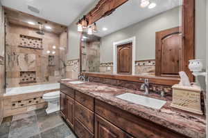 Full bathroom featuring vanity, tile walls, shower / bath combination with glass door, and toilet