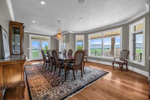 Dining room with crown molding, a notable chandelier, wood-type flooring, a textured ceiling, and a mountain view