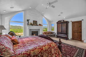 Bedroom with high vaulted ceiling, carpet, ceiling fan, a high end fireplace, and a mountain view