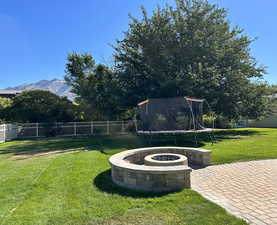 View of yard featuring a patio area, a mountain view, a trampoline, and a fire pit