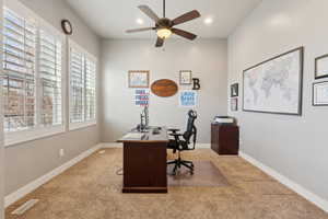 Office space with light carpet and ceiling fan