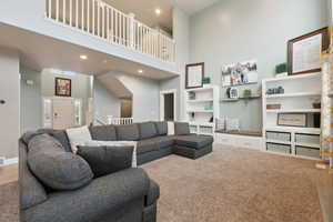 Carpeted living room with built in features and a high ceiling