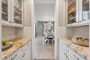 Kitchen featuring white cabinetry, light stone countertops, and light wood-type flooring