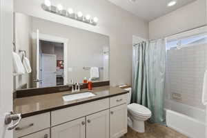 Full bathroom with toilet, vanity, and shower / bathtub combination with curtain