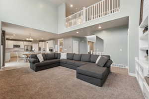 Carpeted living room featuring a towering ceiling