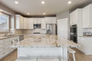 Kitchen featuring sink, stainless steel appliances, a center island, and white cabinets