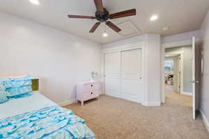 Bedroom with ceiling fan, light carpet, and a closet