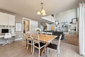 Dining room featuring a notable chandelier, built in desk, light hardwood / wood-style flooring, and a towering ceiling