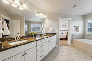 Bathroom featuring tile patterned flooring, vanity, a wealth of natural light, and tiled bath