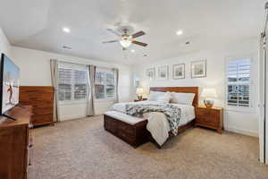 Carpeted bedroom with multiple windows, vaulted ceiling, and ceiling fan