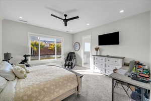 Carpeted bedroom featuring ensuite bath and ceiling fan