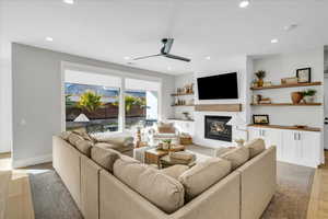 Living room with light hardwood / wood-style flooring, a large fireplace, and ceiling fan