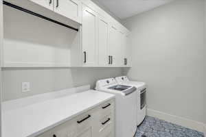 Laundry room with light tile patterned flooring, cabinets, and separate washer and dryer