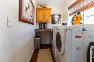 Laundry area featuring washer and dryer, hardwood / wood-style floors, and cabinets