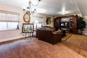 Living room with carpet, a notable chandelier, and a textured ceiling