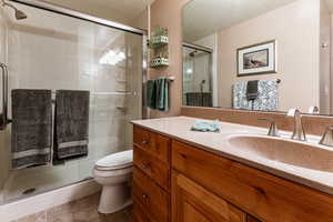 Bathroom with tile patterned floors, toilet, a shower with shower door, a textured ceiling, and vanity