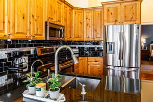 Kitchen with tasteful backsplash, appliances with stainless steel finishes, and sink