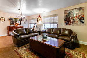 Carpeted living room featuring an inviting chandelier and a textured ceiling