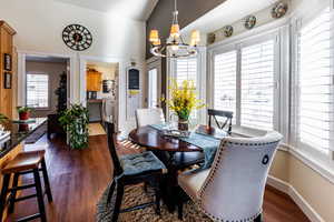 Dining area with an inviting chandelier, dark hardwood / wood-style flooring, and vaulted ceiling