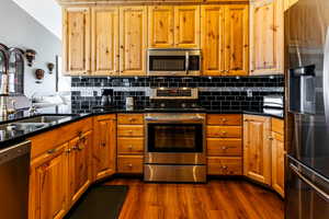 Kitchen featuring stainless steel appliances, sink, backsplash, and dark hardwood / wood-style flooring