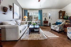 Carpeted living room featuring lofted ceiling and ceiling fan