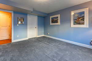 Unfurnished bedroom with dark carpet and a textured ceiling