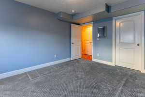 Unfurnished bedroom featuring a textured ceiling and dark colored carpet