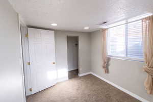 Unfurnished bedroom featuring a closet, carpet flooring, a textured ceiling, and a spacious closet