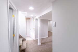 Hallway featuring light colored carpet and a textured ceiling