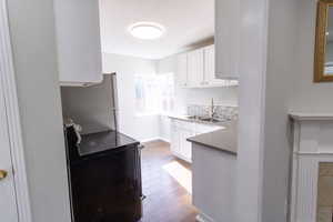 Kitchen with sink, light hardwood / wood-style flooring, stainless steel fridge, electric stove, and white cabinets