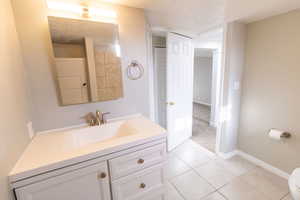 Bathroom featuring tile patterned flooring, vanity, a textured ceiling, and toilet