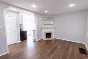 Unfurnished living room featuring a tile fireplace, dark hardwood / wood-style floors, and a textured ceiling