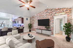 Living room with lofted ceiling, sink, light carpet, ceiling fan, and brick wall