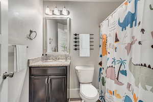 Bathroom featuring vanity, curtained shower, and toilet