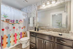 Bathroom with a shower with curtain, vanity, and toilet