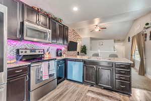 Kitchen featuring sink, decorative backsplash, kitchen peninsula, stainless steel appliances, and dark brown cabinets