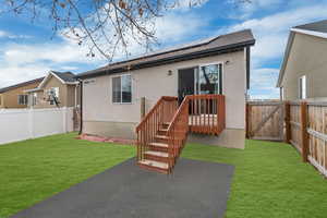 Back of house featuring a yard and solar panels