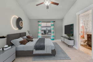 Bedroom featuring vaulted ceiling, light colored carpet, ceiling fan, and ensuite bathroom