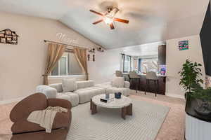 Carpeted living room featuring lofted ceiling and ceiling fan