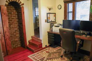 Home office featuring hardwood floors and brick wall