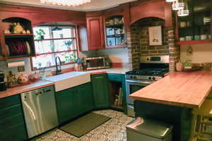 Kitchen featuring butcher block countertops, brick wall inset for stove, built in shelves, SS appliances