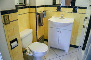 Bathroom featuring vanity, tile walls, and cast iron bathtub.